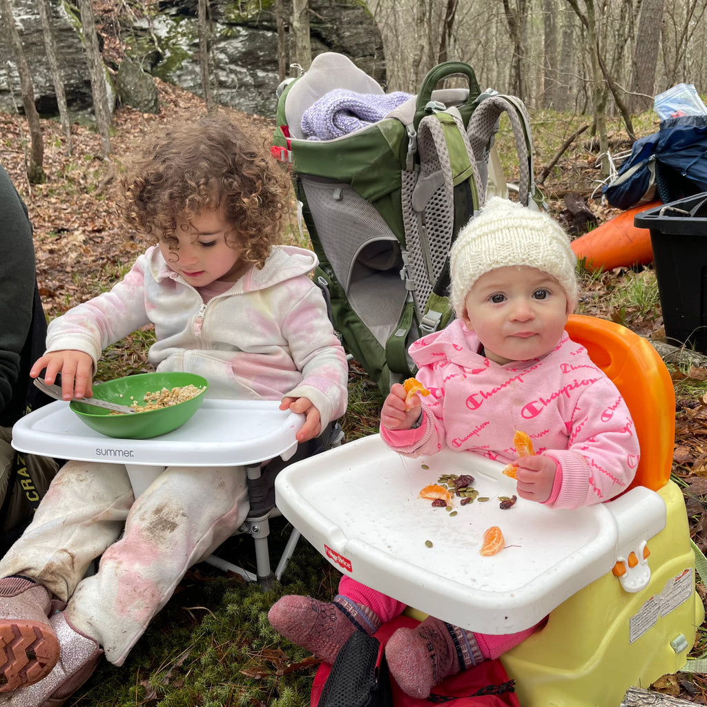 a toddler and an infant in a camping chair