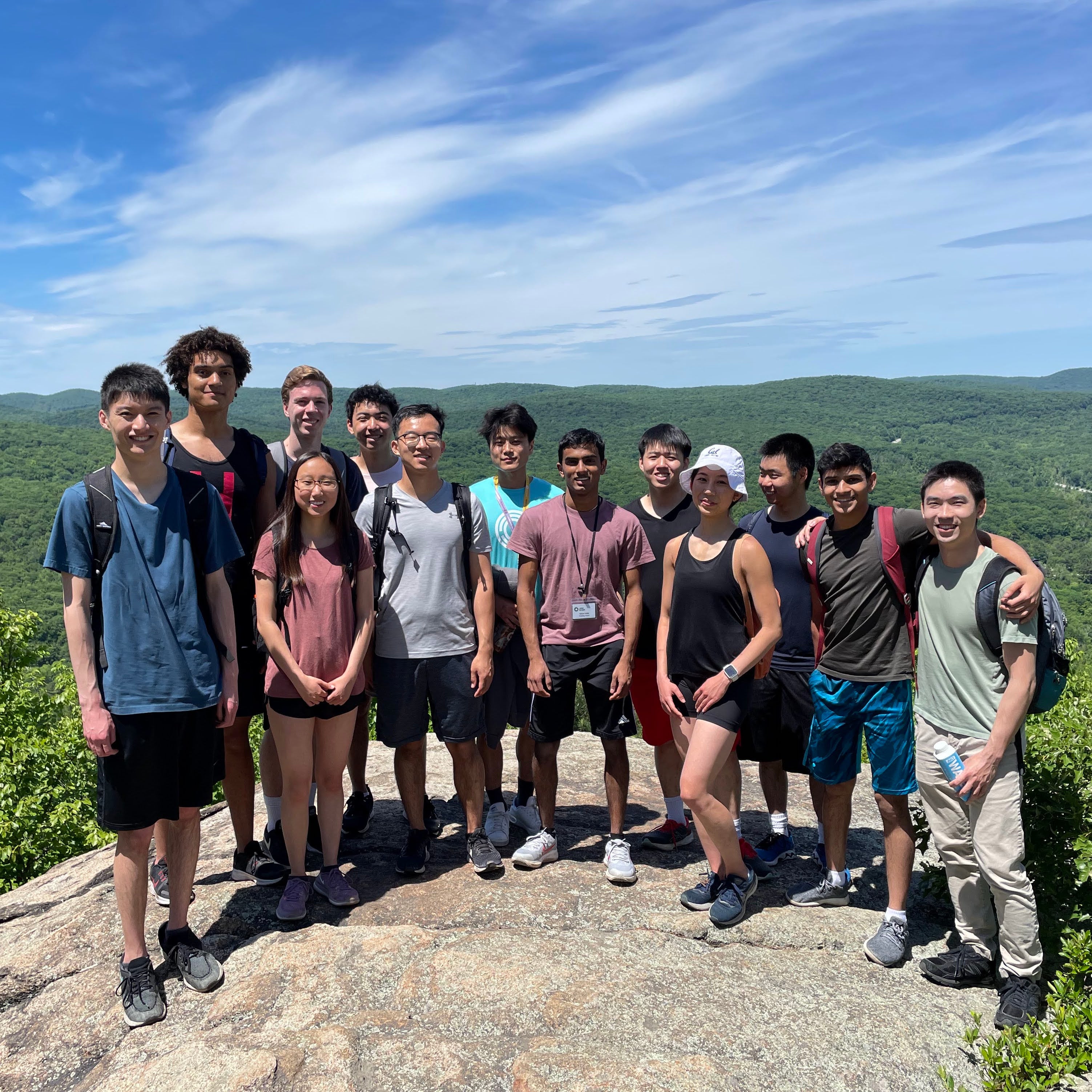a group of hikers poses on a mountaintop viewpoint