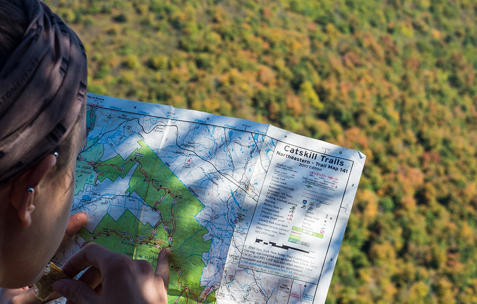 woman looking at a map on a mountain summit