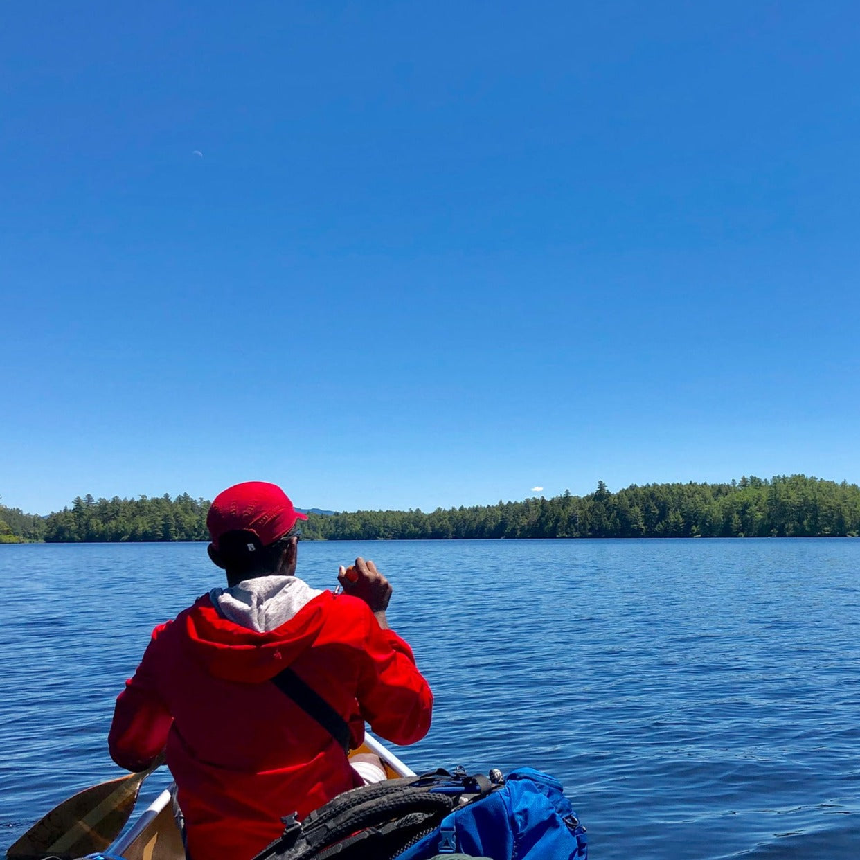 a person in a red jacket paddling on colgate lake in the Catskills