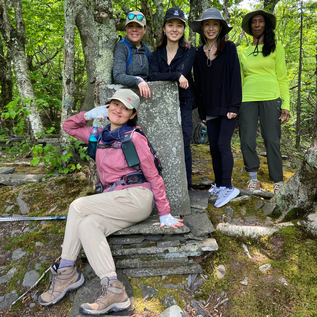 one hiker poses in a stone chair and 4 pose on trail during a hike