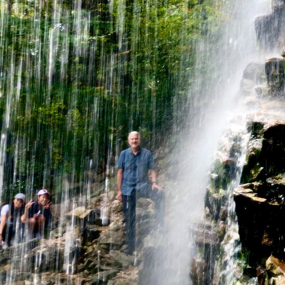 People standing near a waterfall with water cascading down rocks