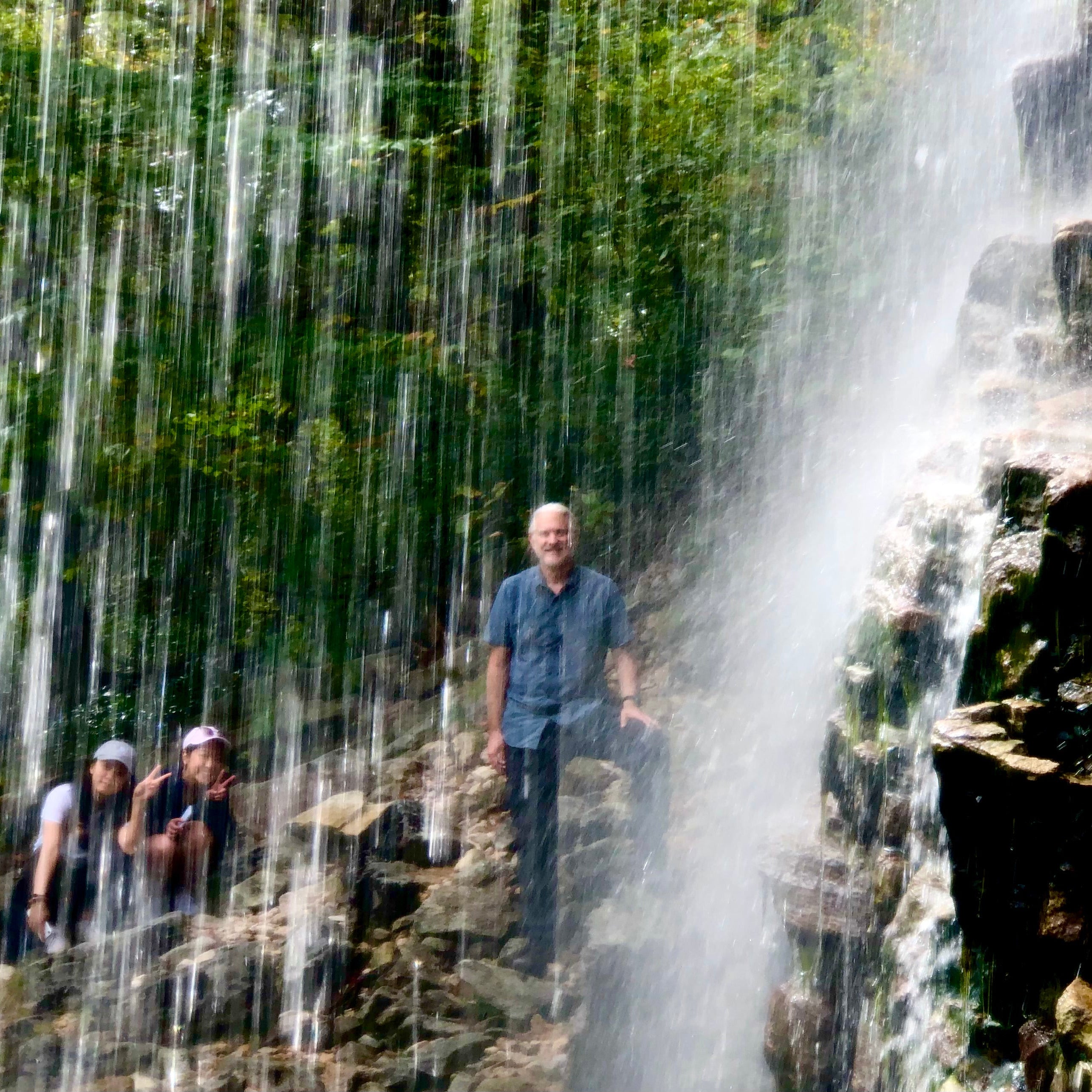 People standing near a waterfall with water cascading down rocks