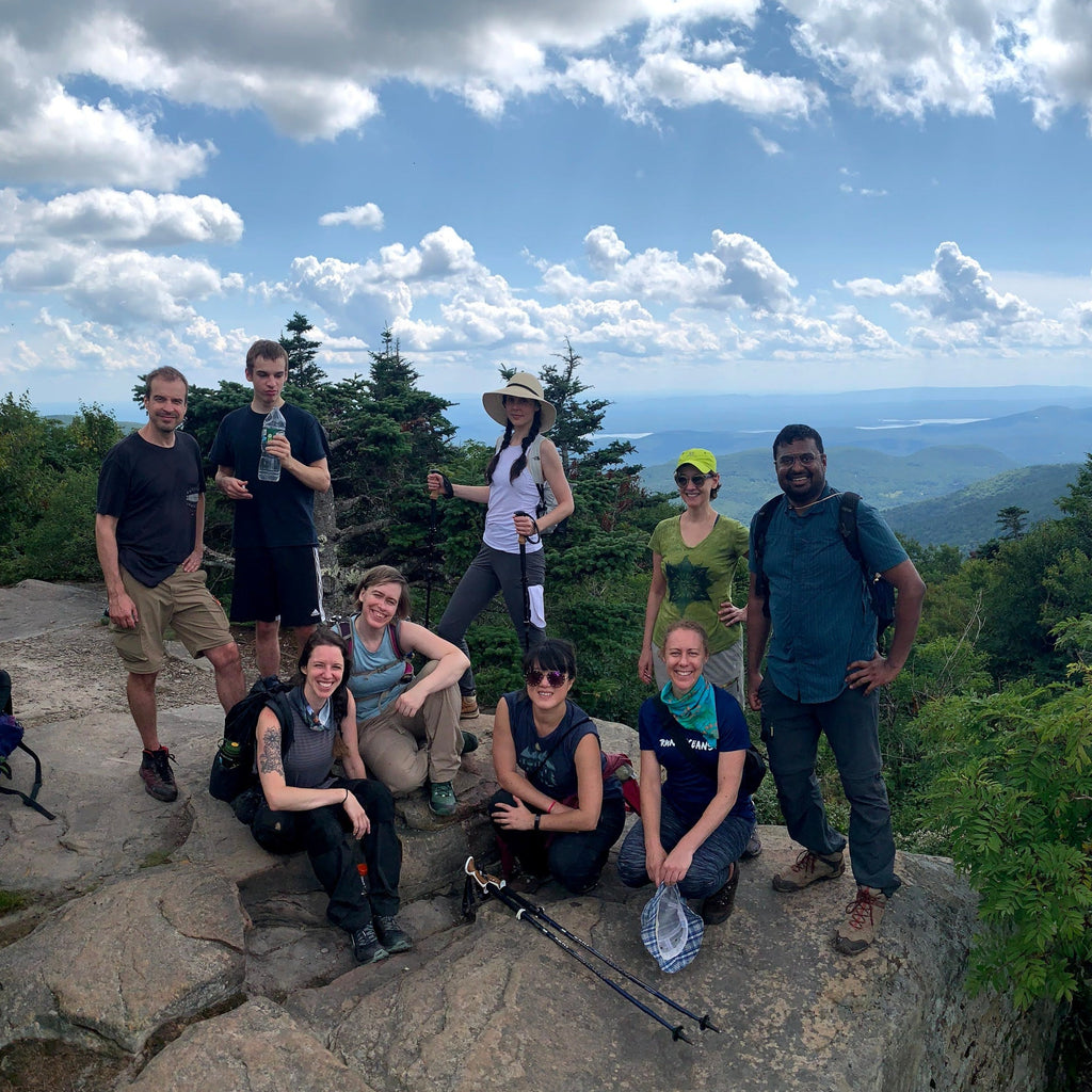 a group poses on the top of twin mountain in the summer