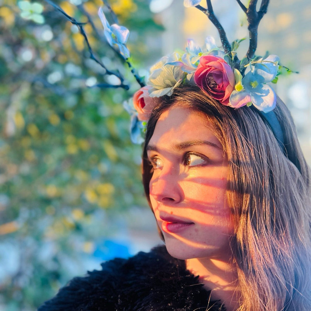 a woman poses in a stick and flower crown in the forest
