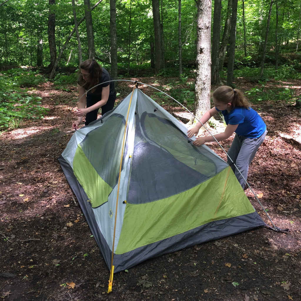 a mother and daughter work together to set up a tent