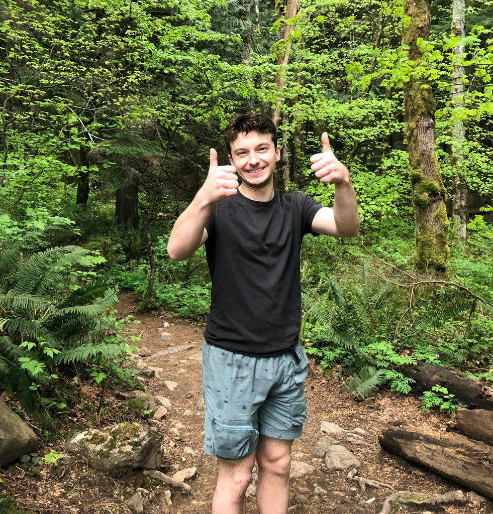 apprentice guide tom bentsen posing on trail in a lush forest giving two thumbs ups to the camera