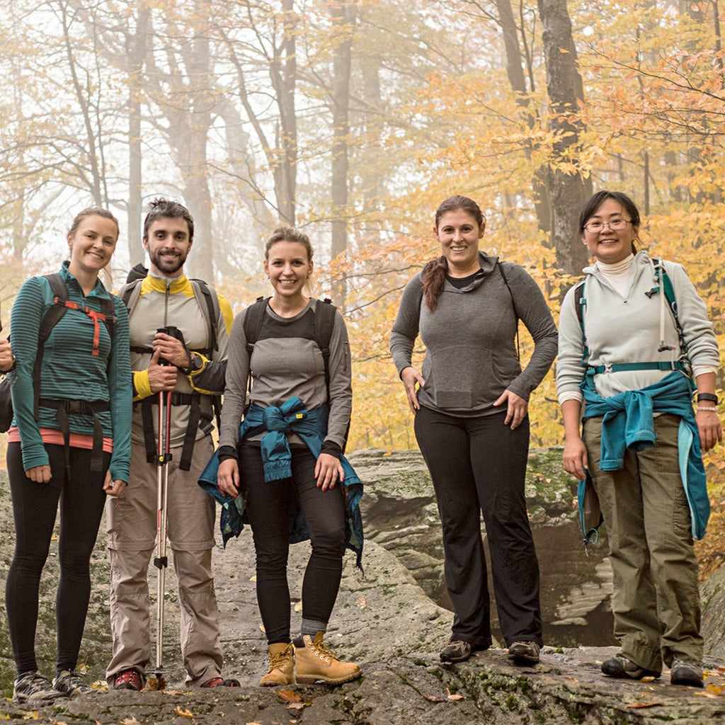 five hikers pose on trail with fall foliage behind them