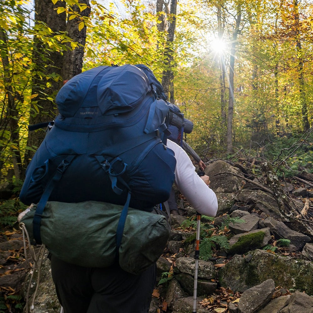 a backpacker with an overnight pack looking up at a rocky trail